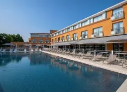 un grand bâtiment orange devant lequel se trouve une piscine