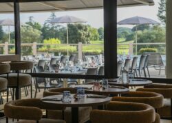 tables et chaises dans un restaurant avec vue sur un terrain de golf