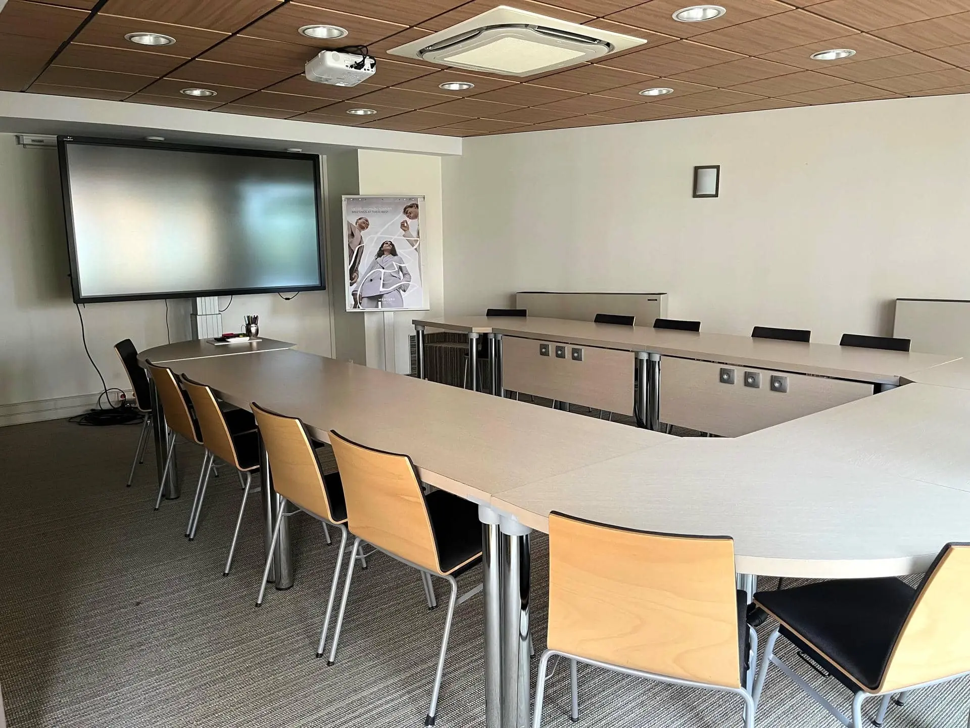 une salle de conférence avec des tables et des chaises et un grand écran