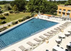 Grande piscine avec vue sur le golf, équipée de buses et d’un bec d’eau pour se détendre, bordée par la grande terrasse du restaurant séminaire.