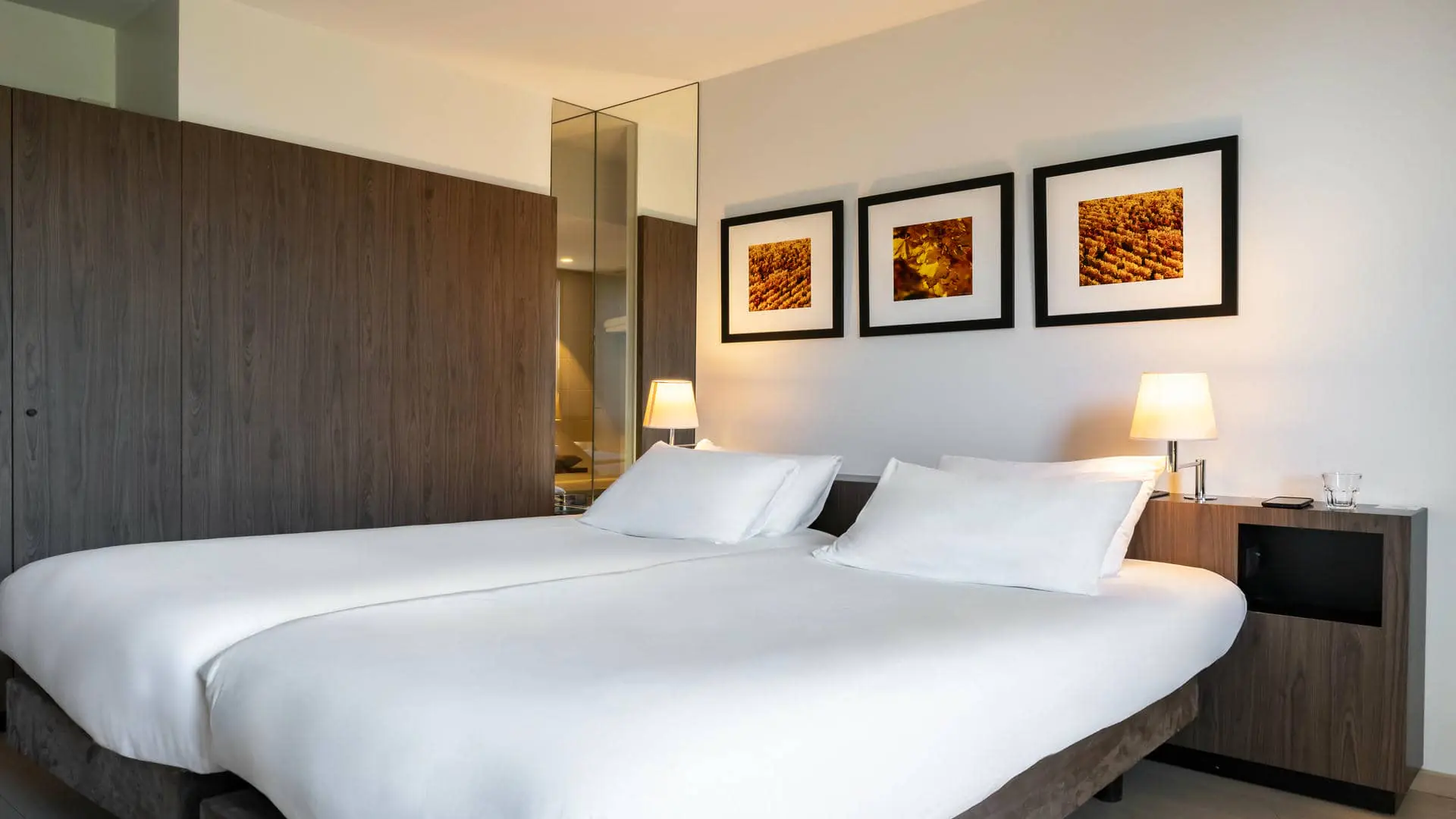 A hotel room with a black wall-mounted television, a brown wardrobe, and a black suit jacket hanging from a wall hook.