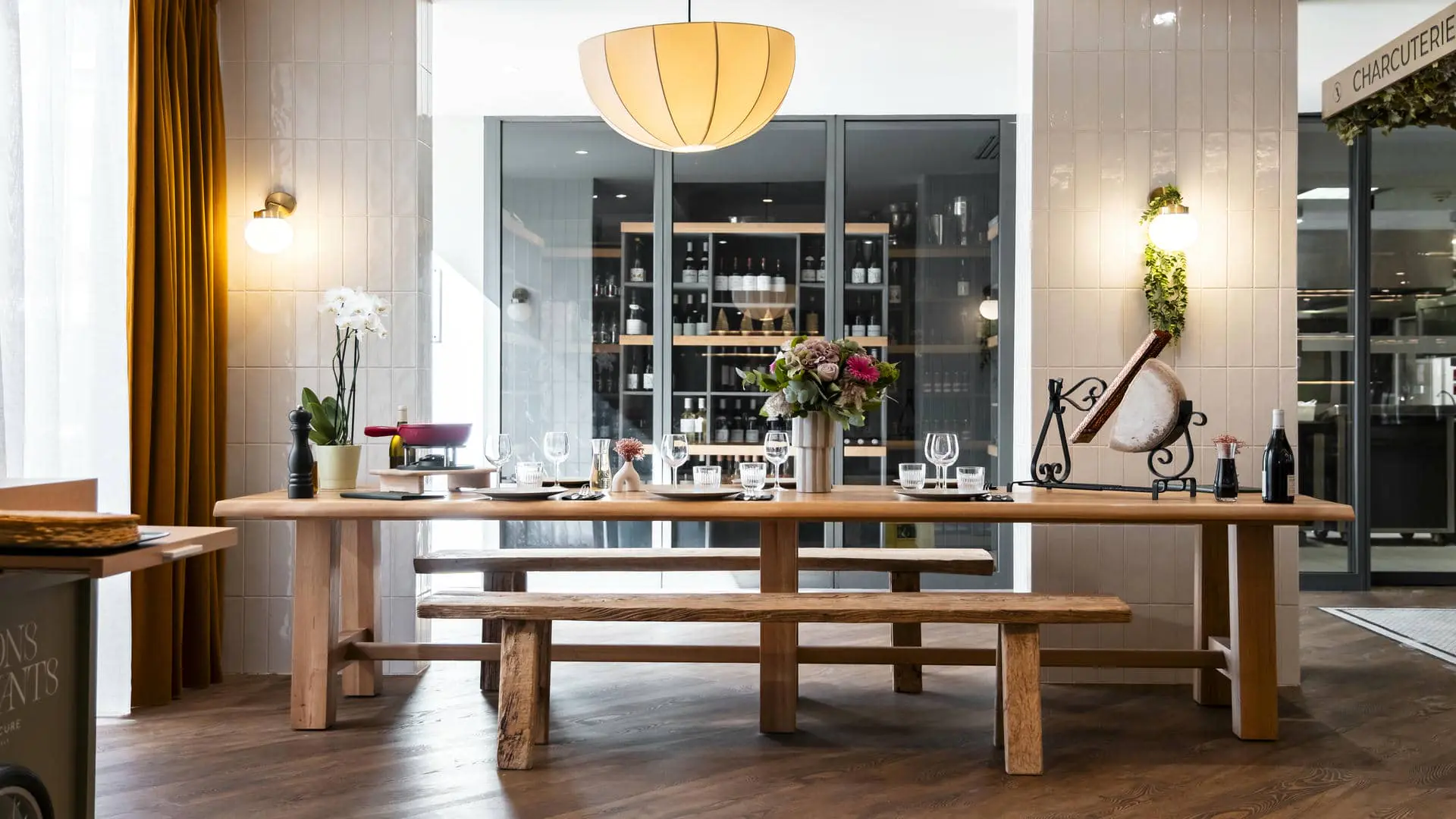 A wooden communal dining table set for raclette and fondue, with a view of the restaurant’s wine cellar, ideal for seminars and group dining.