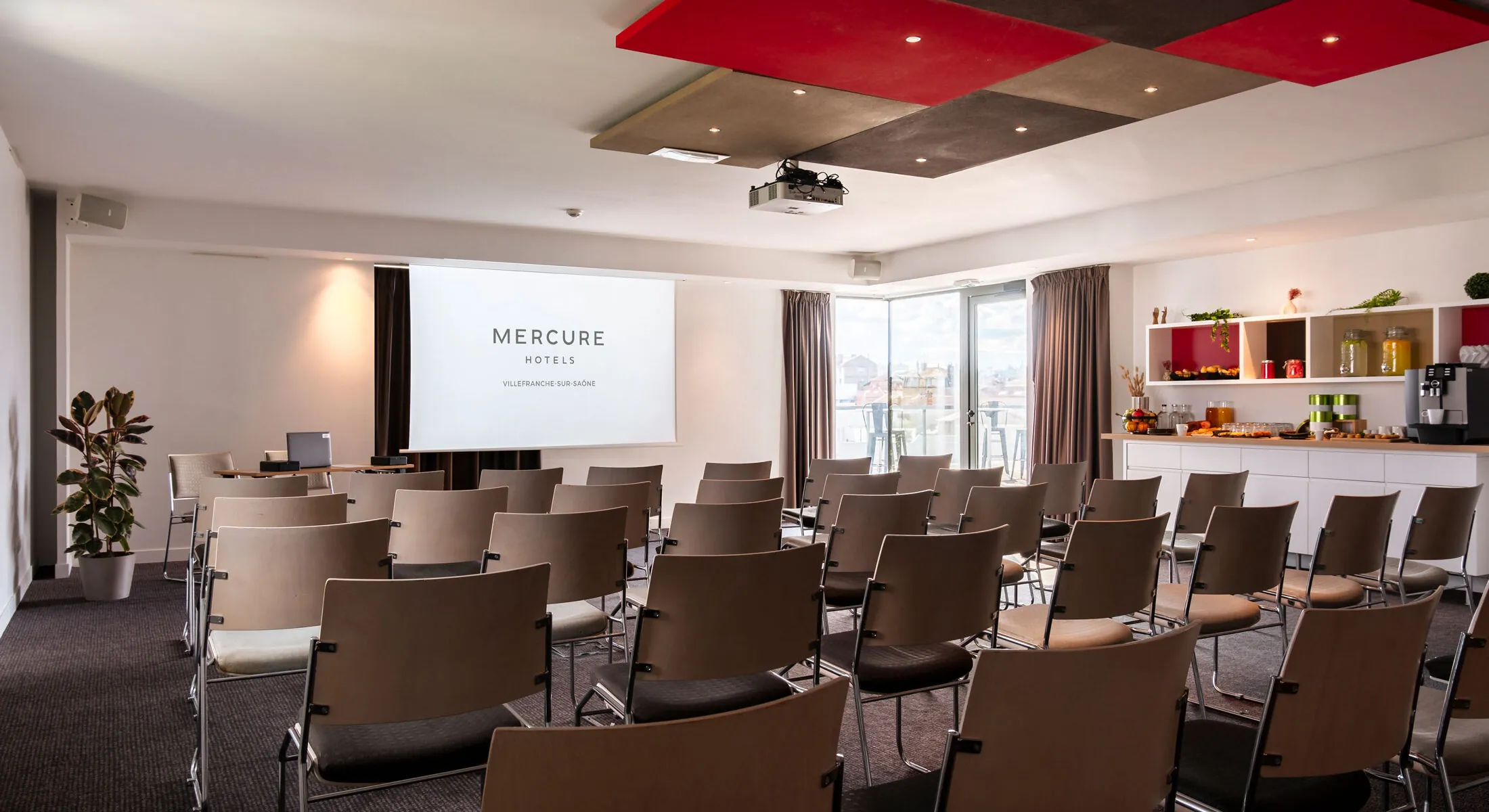 une salle avec des rangées de chaises et un écran de projection sur lequel sont inscrits les hôtels mercure