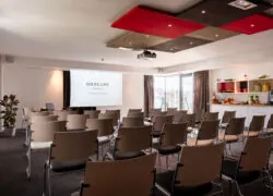 a room with rows of chairs and a projector screen that says mercure hotels