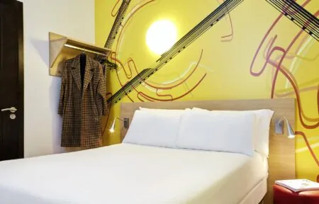 une chambre avec un mur jaune et un lit blanc