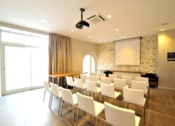 une salle avec des chaises blanches et un projecteur au plafond