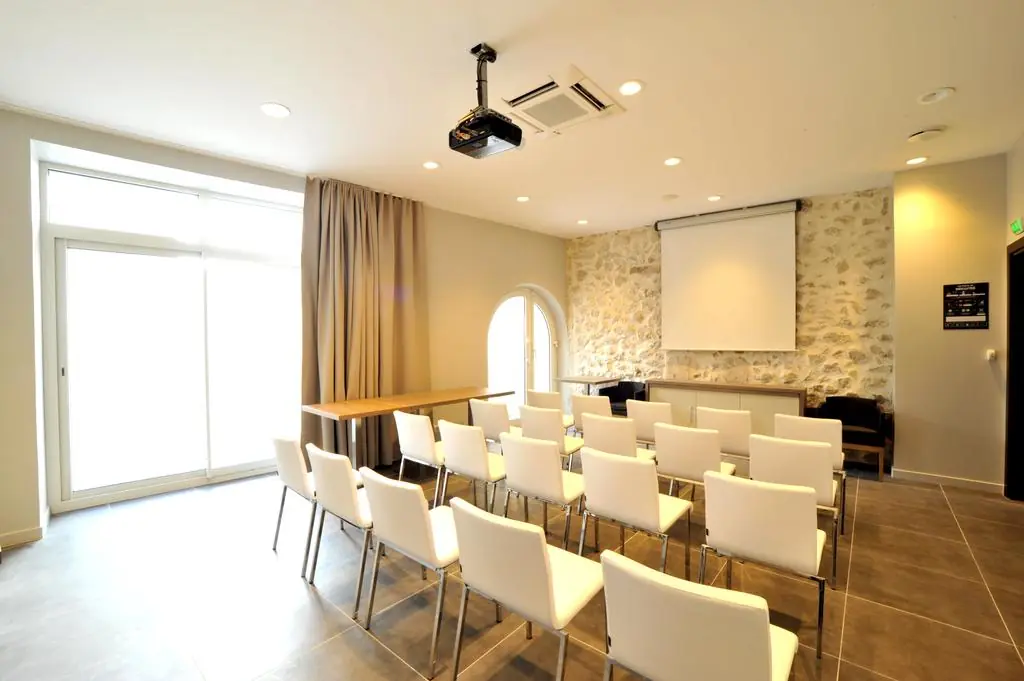 une salle avec des chaises blanches et un projecteur au plafond