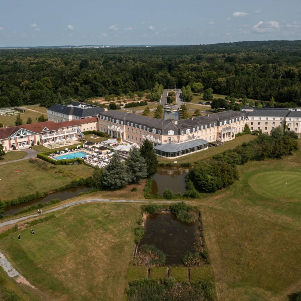 an aerial view of a large hotel Mercure Chantilly surrounded by trees
