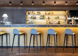 a row of bar stools are lined up in front of a bar with bottles of alcohol on shelves