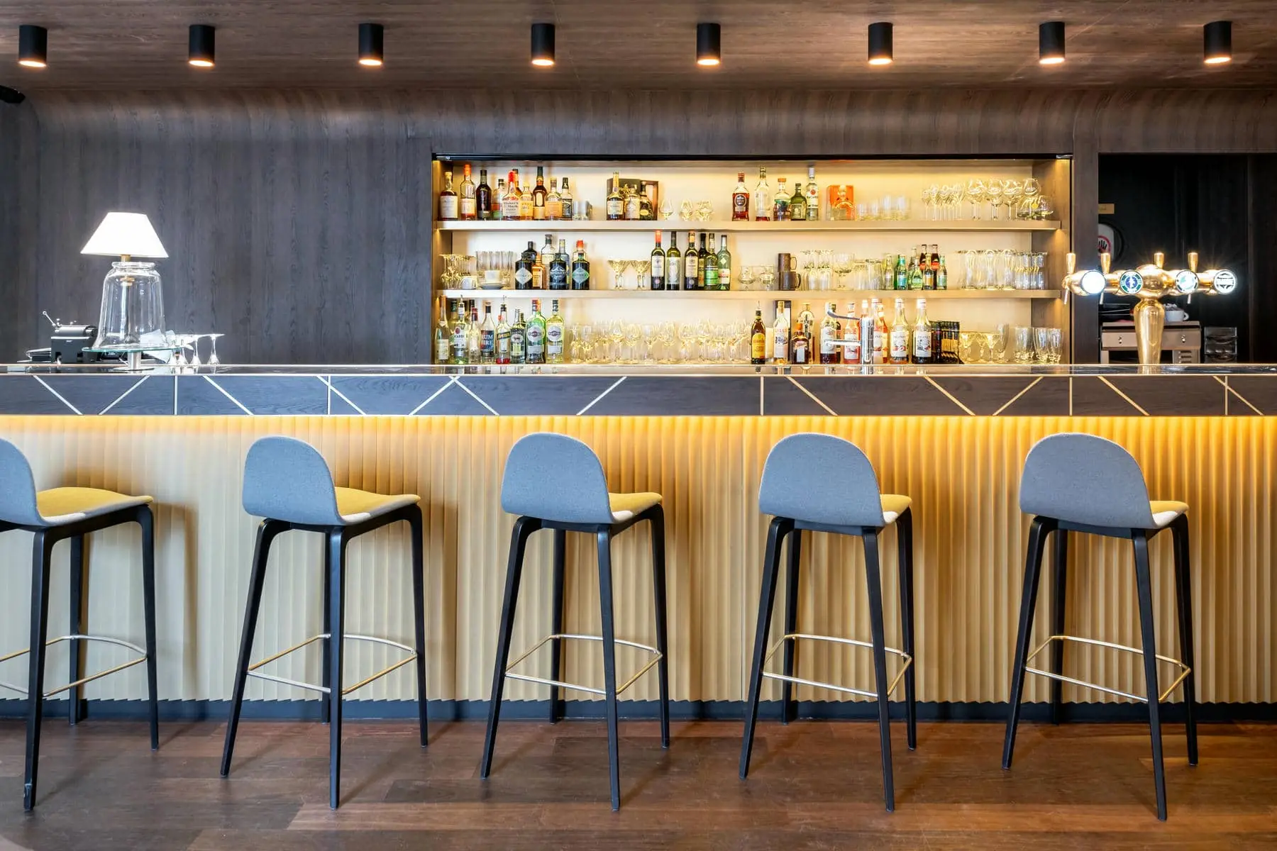 a row of bar stools are lined up in front of a bar with bottles of alcohol on shelves