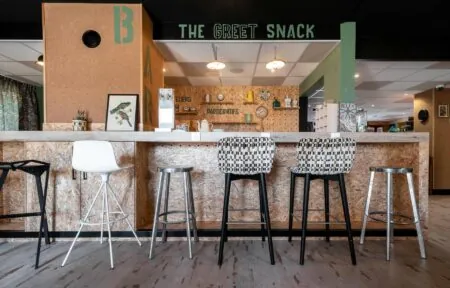 une rangée de tabourets de bar devant un comptoir qui annonce la collation de bienvenue