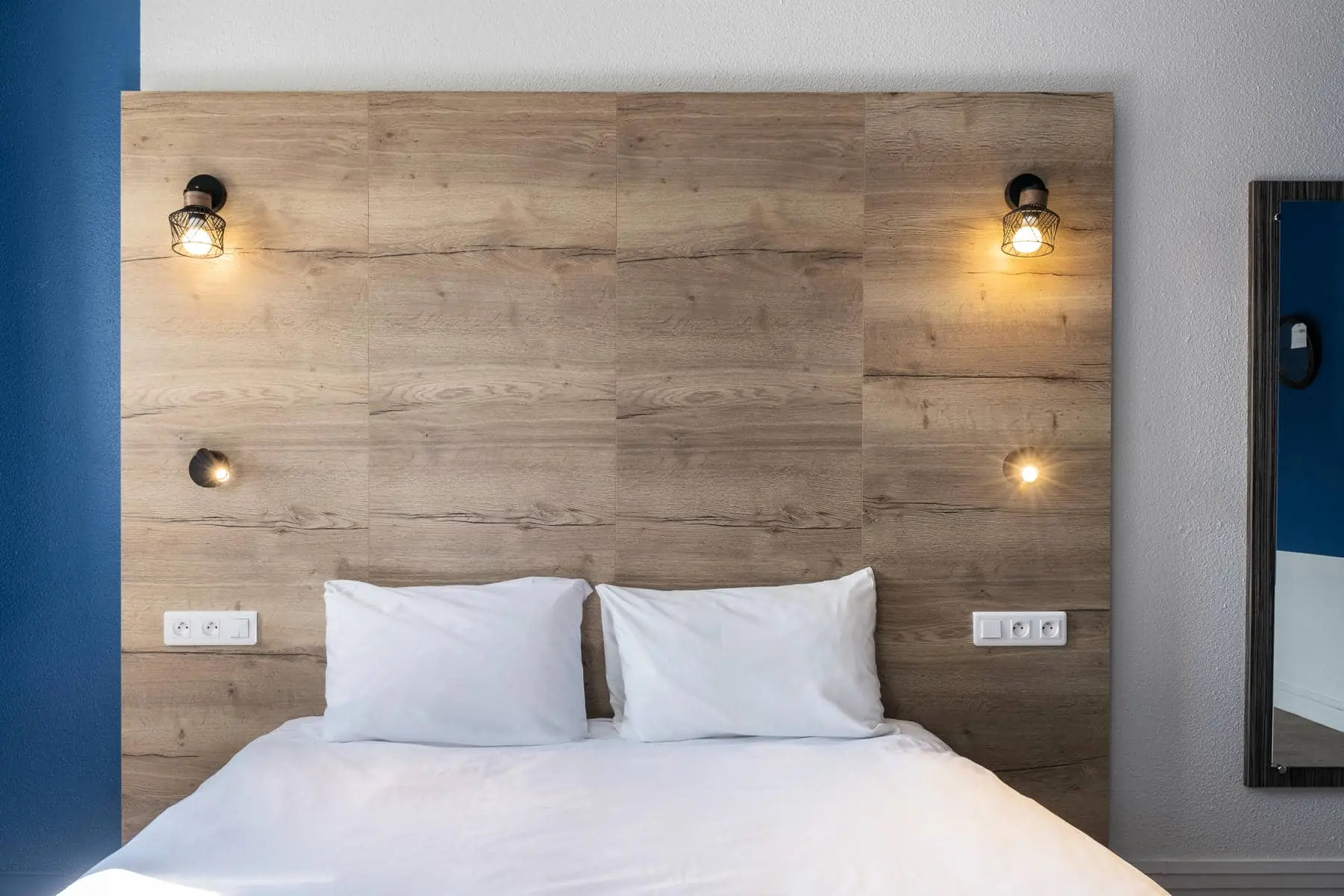 un lit avec des draps blancs et une tête de lit en bois