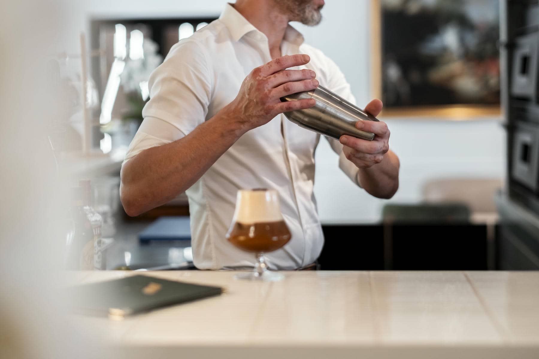un homme en chemise blanche verse une boisson dans un verre