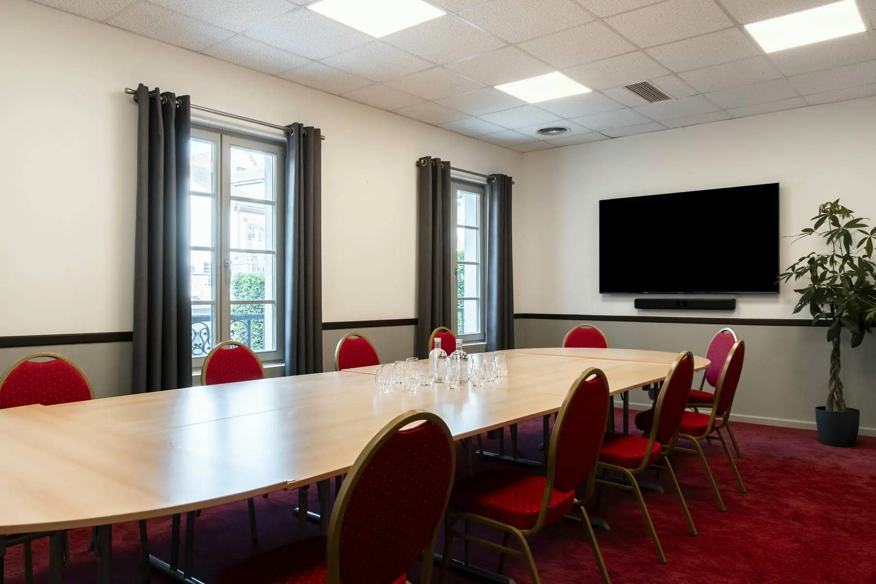 une salle de conférence avec une longue table et des chaises rouges