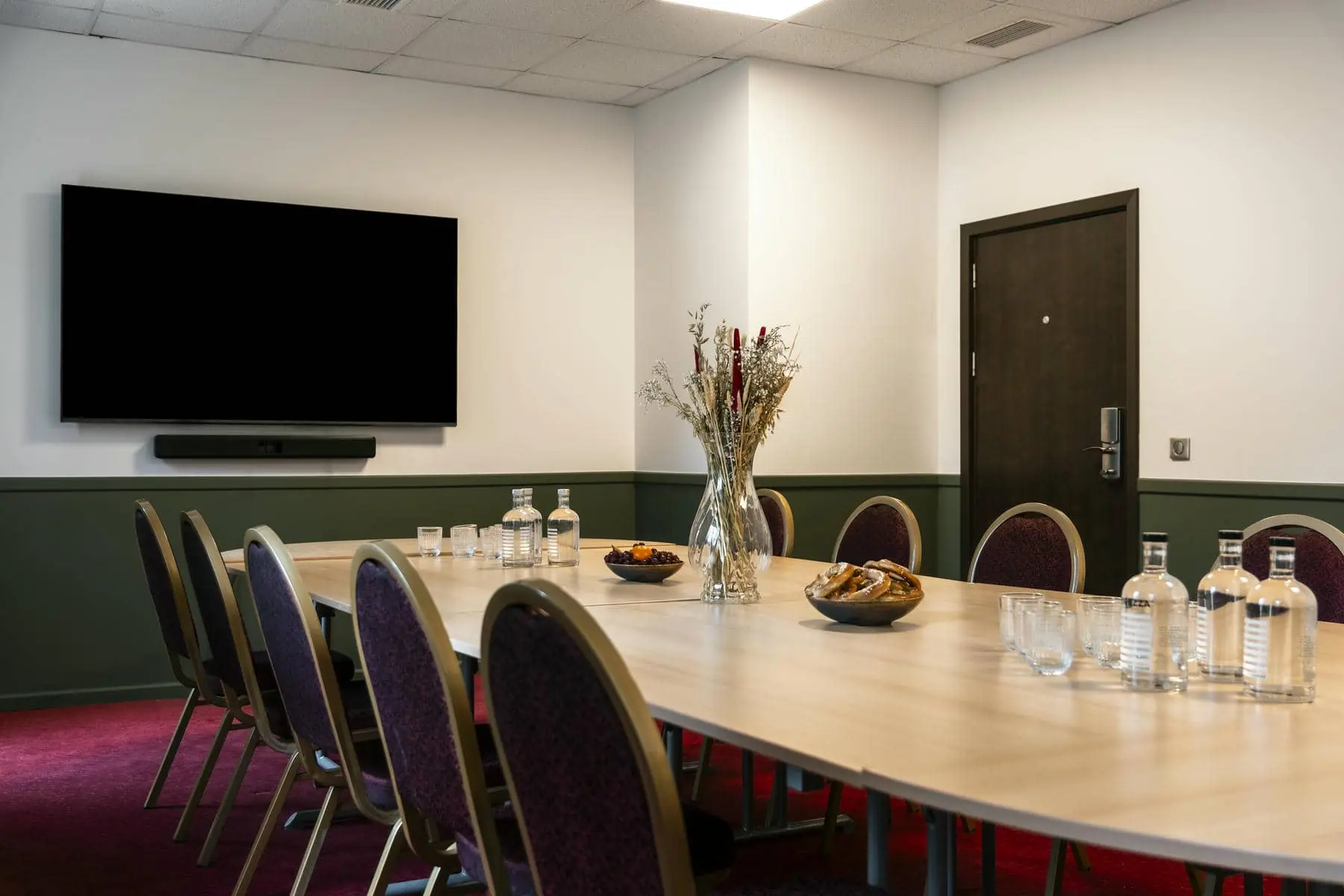 une salle de conférence avec une longue table, des chaises et des bouteilles d'eau aquafina