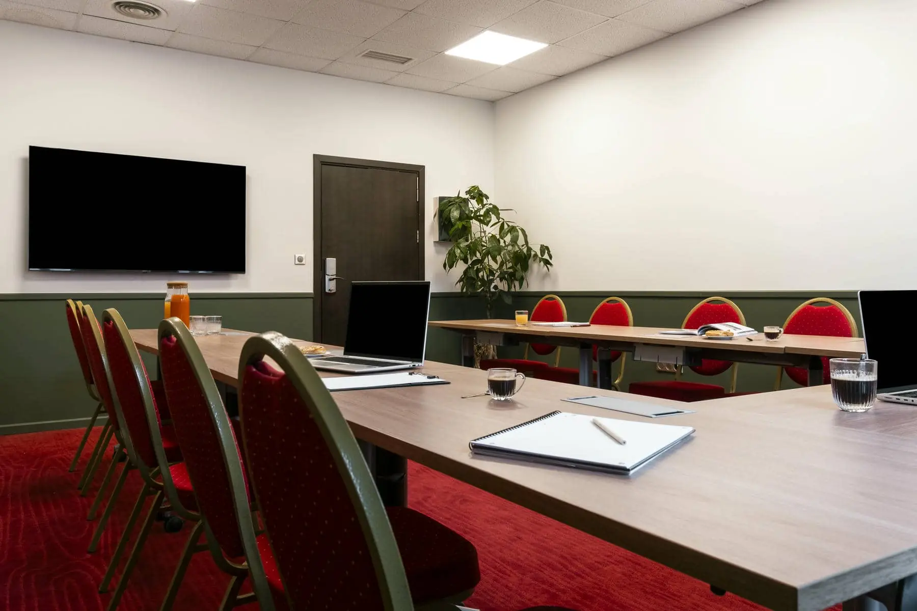 une salle de conférence avec de longues tables et des chaises rouges