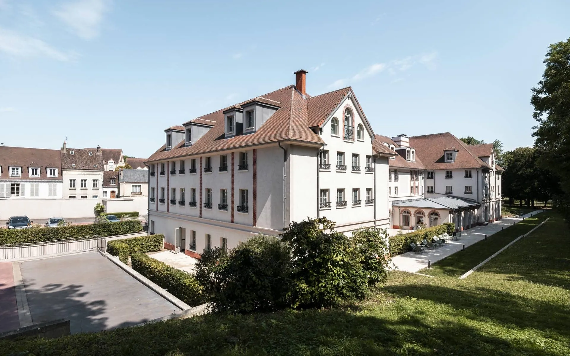 un grand bâtiment blanc avec un toit rouge et un parking accessible