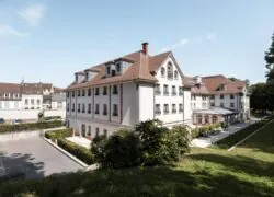 un grand bâtiment blanc avec un toit rouge et un parking accessible