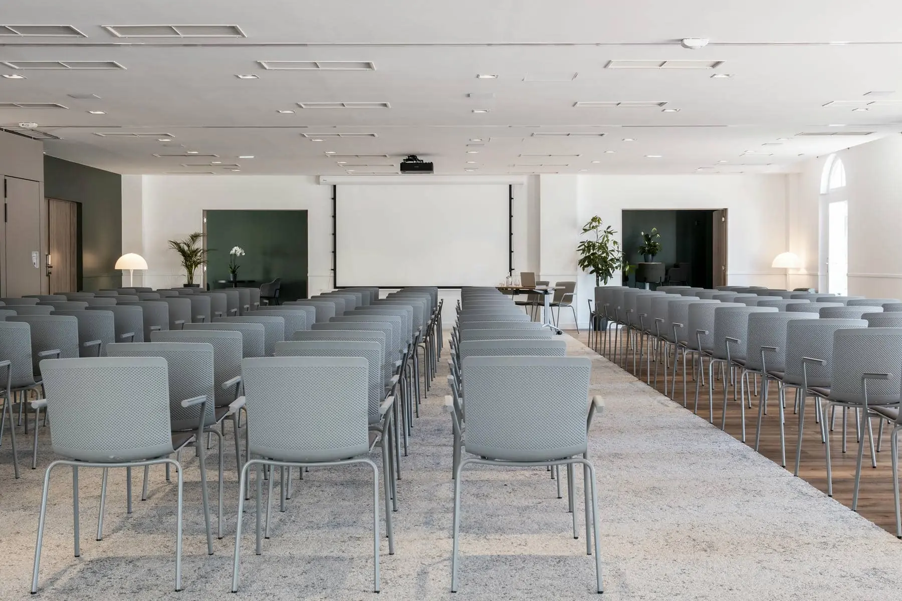 des rangées de chaises sont alignées devant un écran de projection