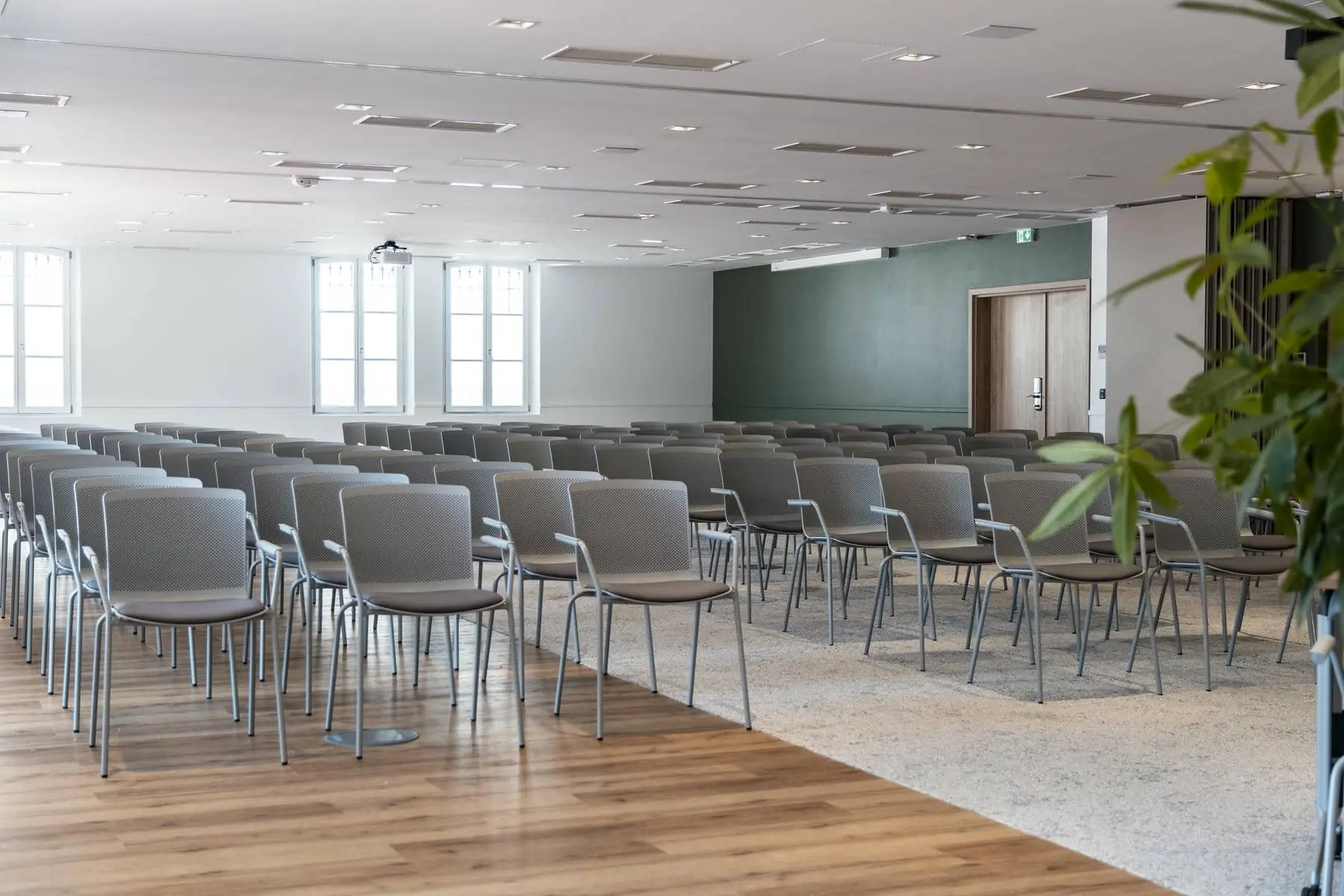 des rangées de chaises dans une grande salle avec un mur vert