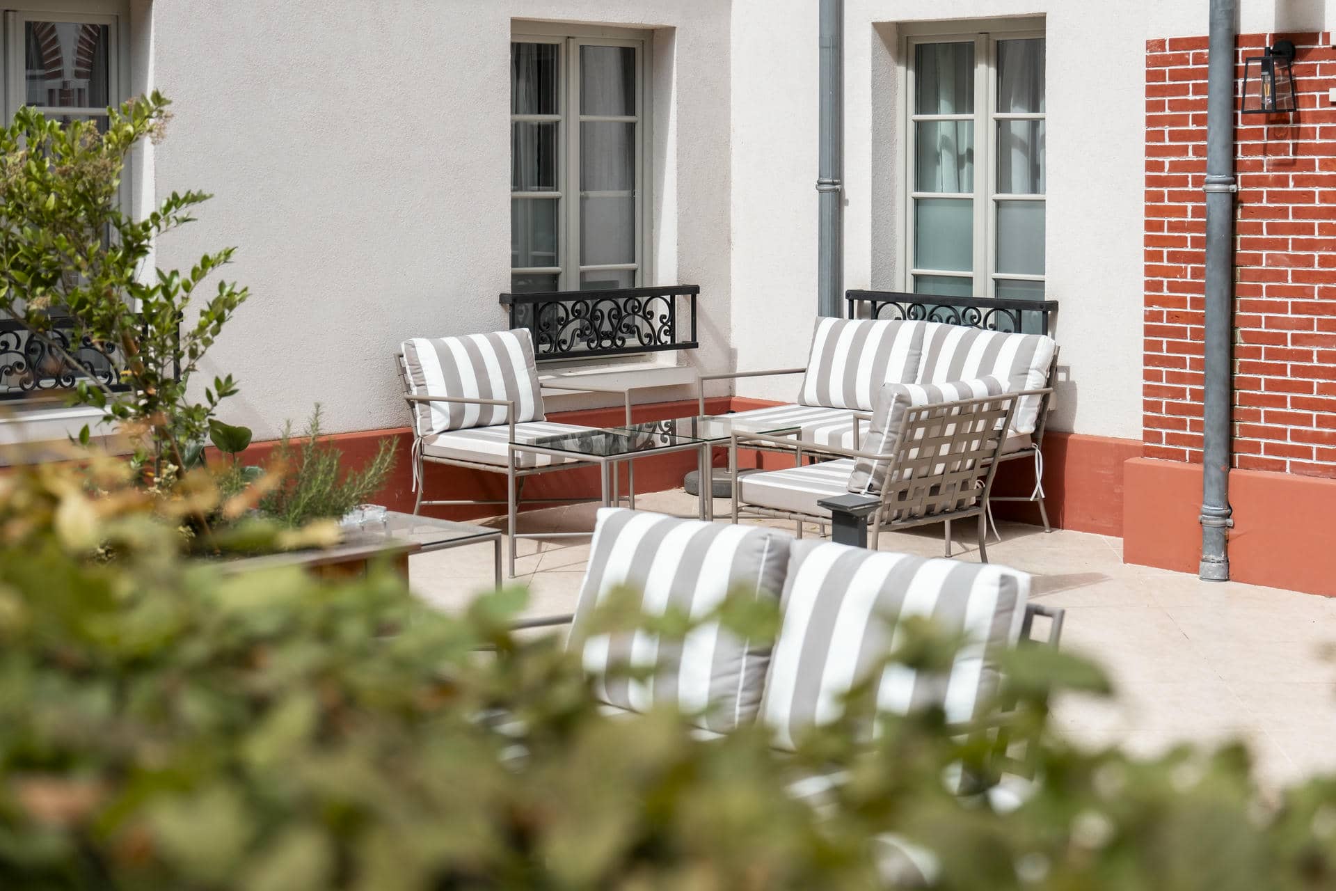 un patio avec un canapé et des chaises devant un bâtiment en briques