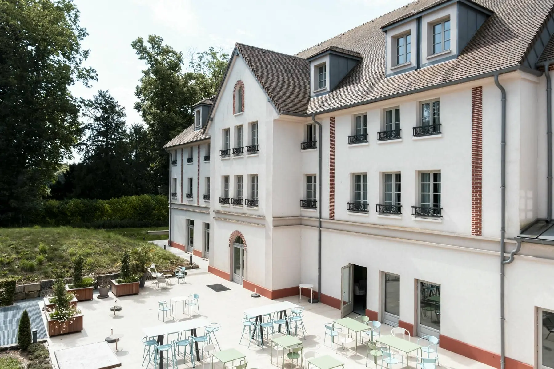 un grand bâtiment blanc devant lequel se trouvent des tables et des chaises