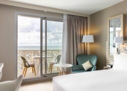 une chambre d'hôtel avec une porte coulissante en verre donnant sur un balcon