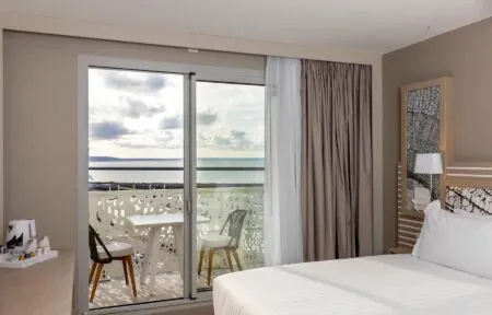 une chambre d'hôtel avec une porte coulissante en verre menant à un balcon donnant sur l'océan