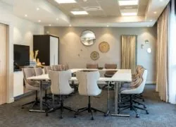 une salle de conférence avec des tables et des chaises et un miroir au mur