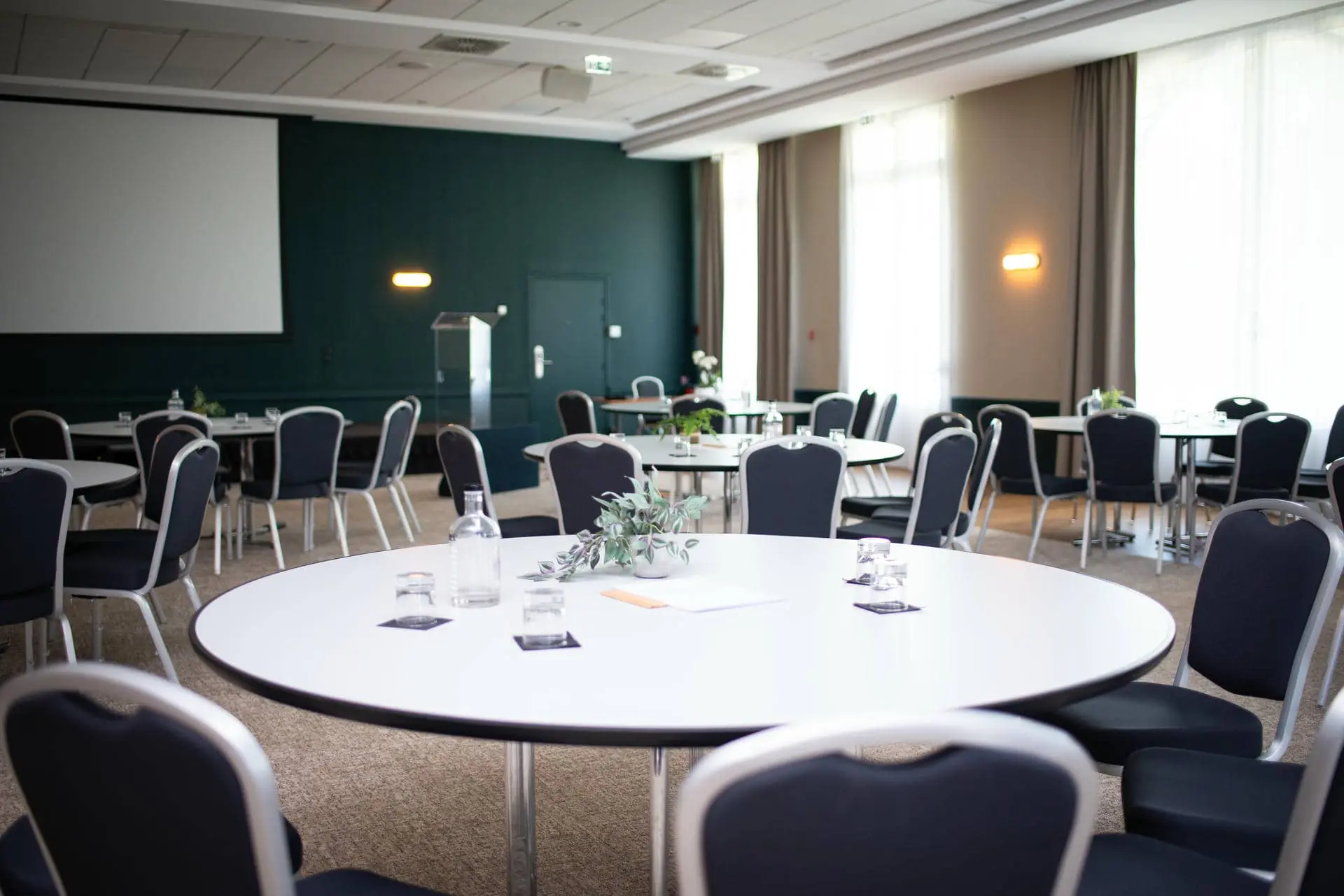 une salle de conférence avec des tables rondes et des chaises noires