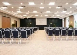 une grande salle avec des rangées de chaises et un écran de projection sur lequel est inscrit mercure