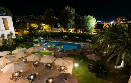 une grande piscine entourée de tables et de parasols le soir