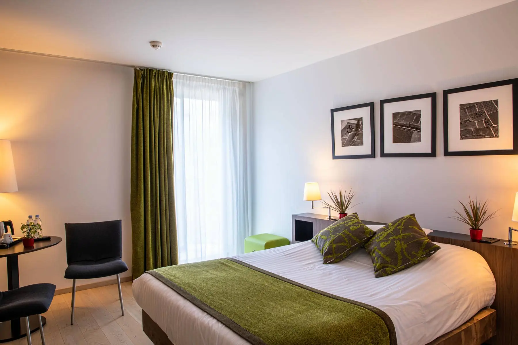 une chambre d'hôtel avec un lit et trois tableaux au mur