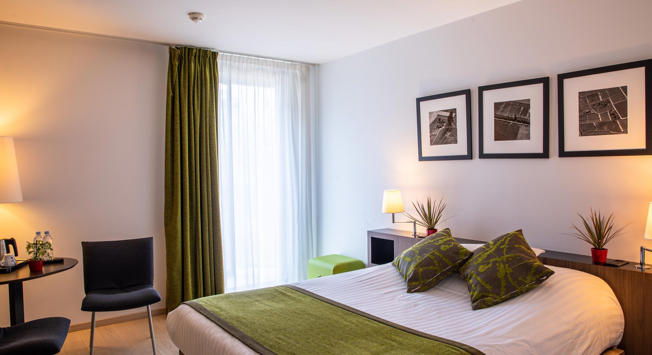 une chambre d'hôtel avec un lit et trois tableaux au mur