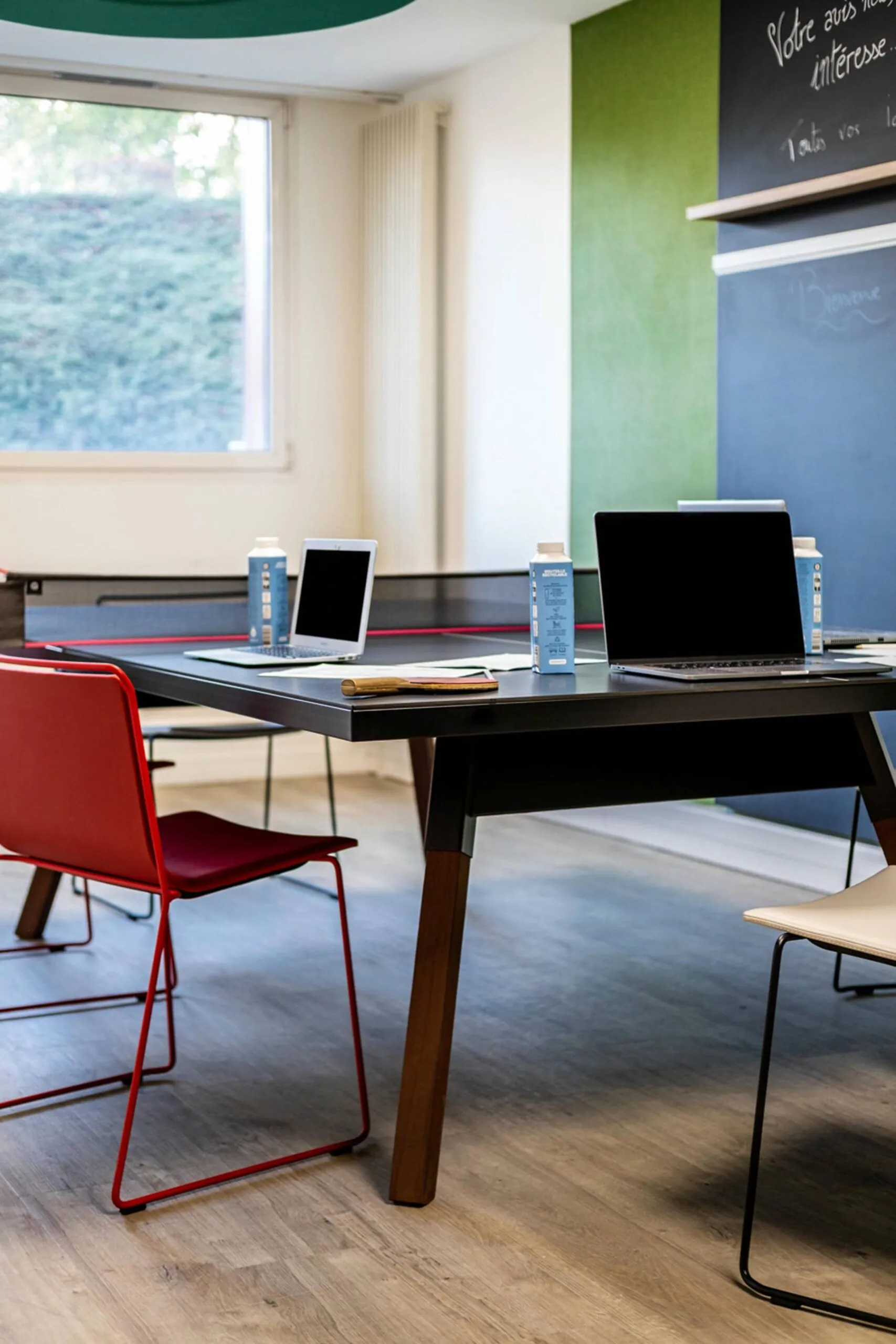 deux ordinateurs portables sont posés sur une table devant un tableau noir sur lequel est inscrit votre