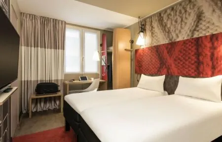 a hotel room with two beds a desk and a television