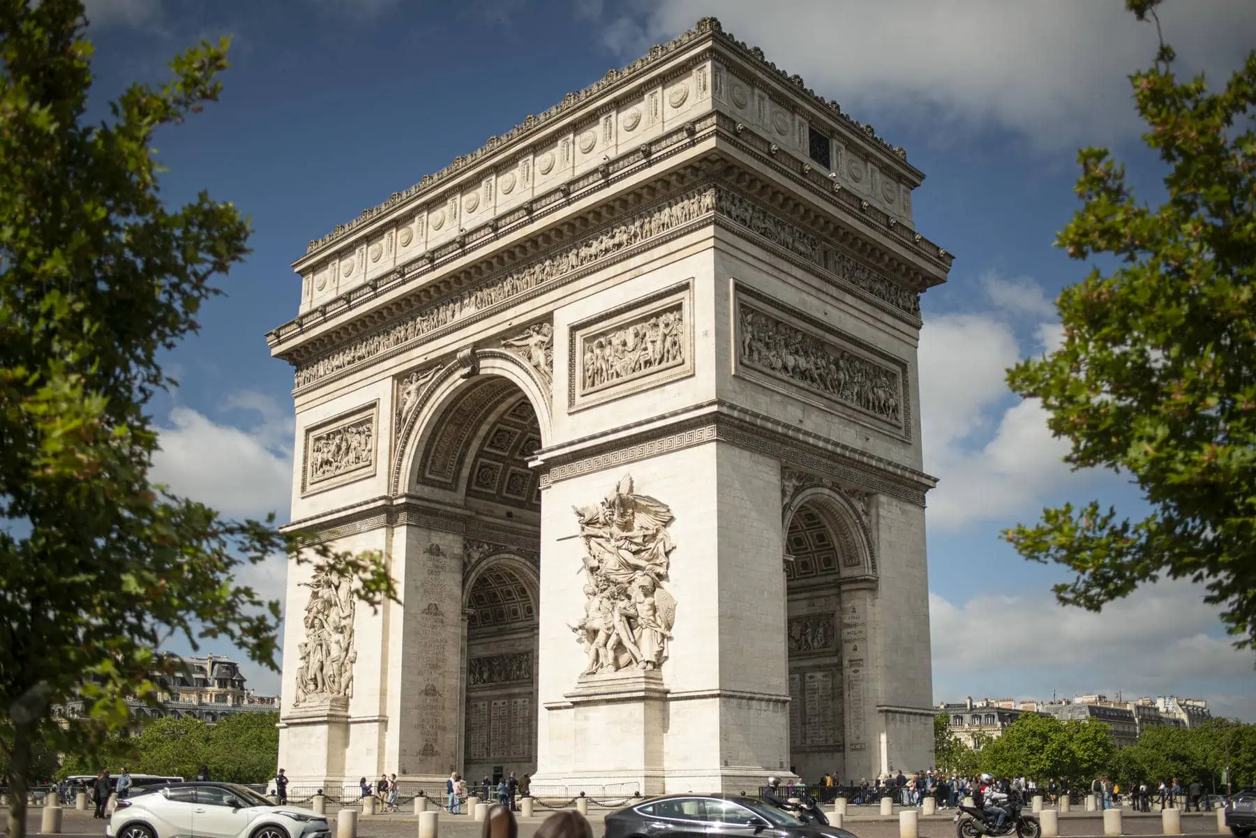 l'arc de triomphe de paris est entouré de voitures et d'arbres