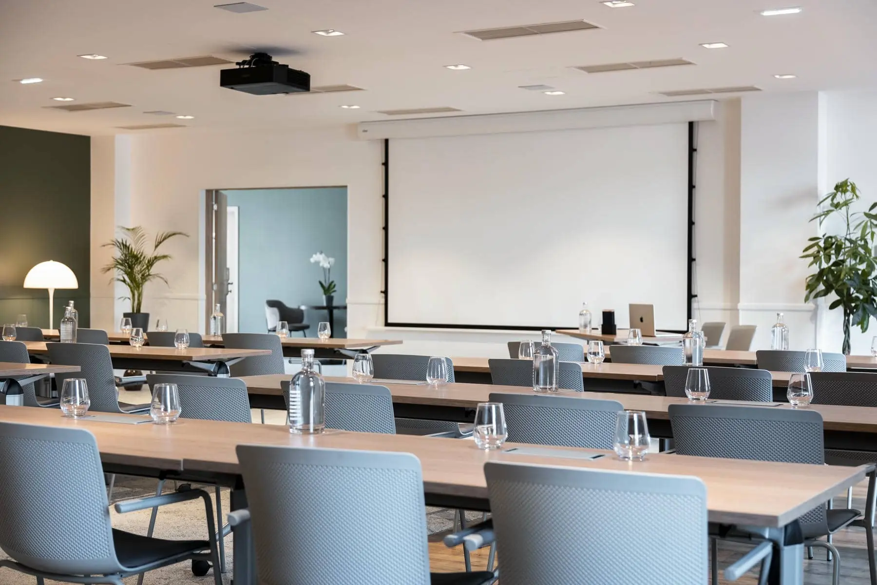 une salle de conférence avec des tables et des chaises et un écran de projection