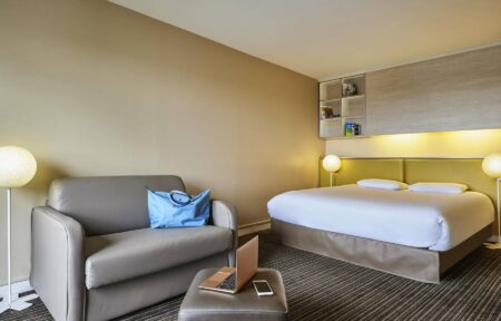 une chambre d'hôtel avec un lit, une chaise et un ordinateur portable