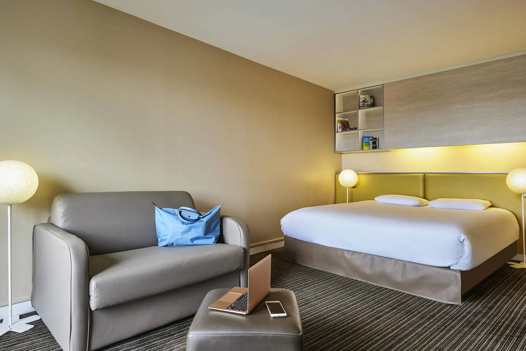 a hotel room with a bed a chair and a laptop