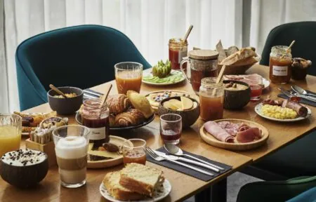 a table topped with a variety of food including a jar of fruit jam