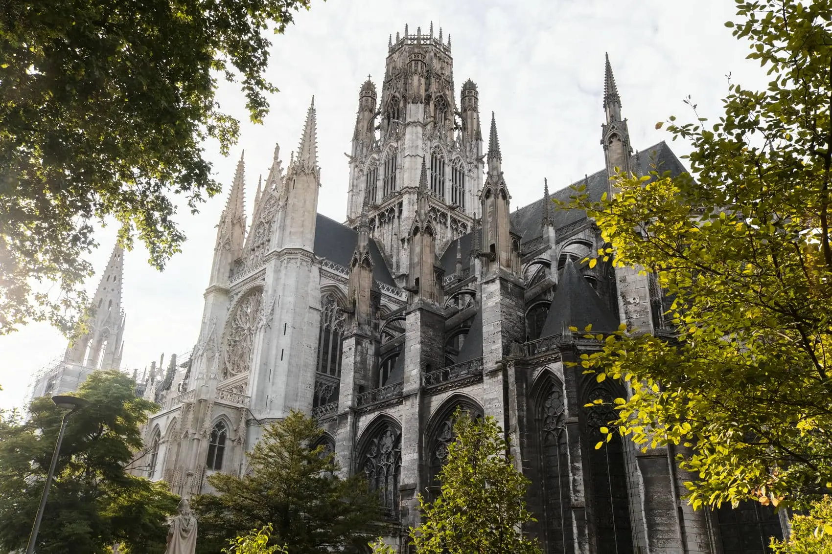 un grand bâtiment blanc avec une très haute tour entourée d'arbres