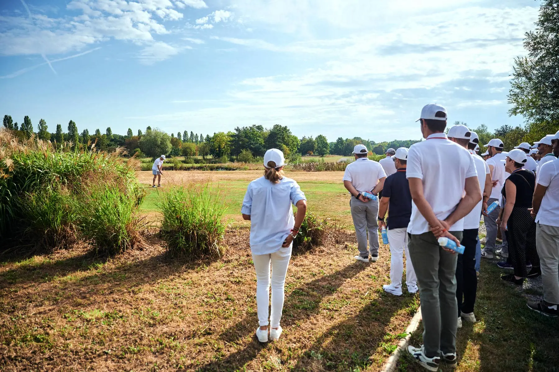 un groupe de personnes regarde un homme jouer au golf