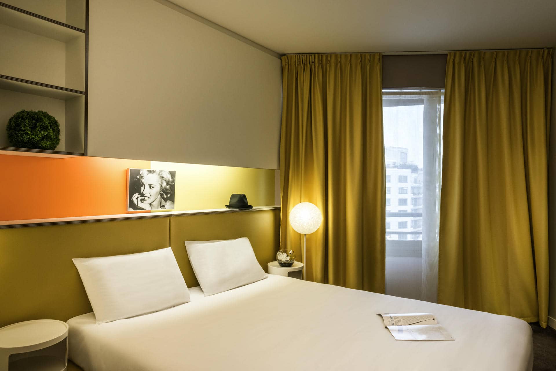 a hotel room with yellow curtains and a bed