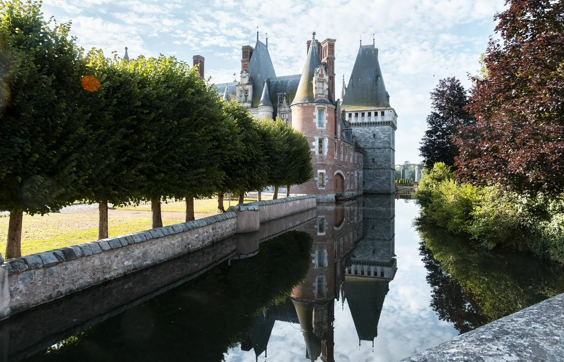 a castle is reflected in a body of water surrounded by trees