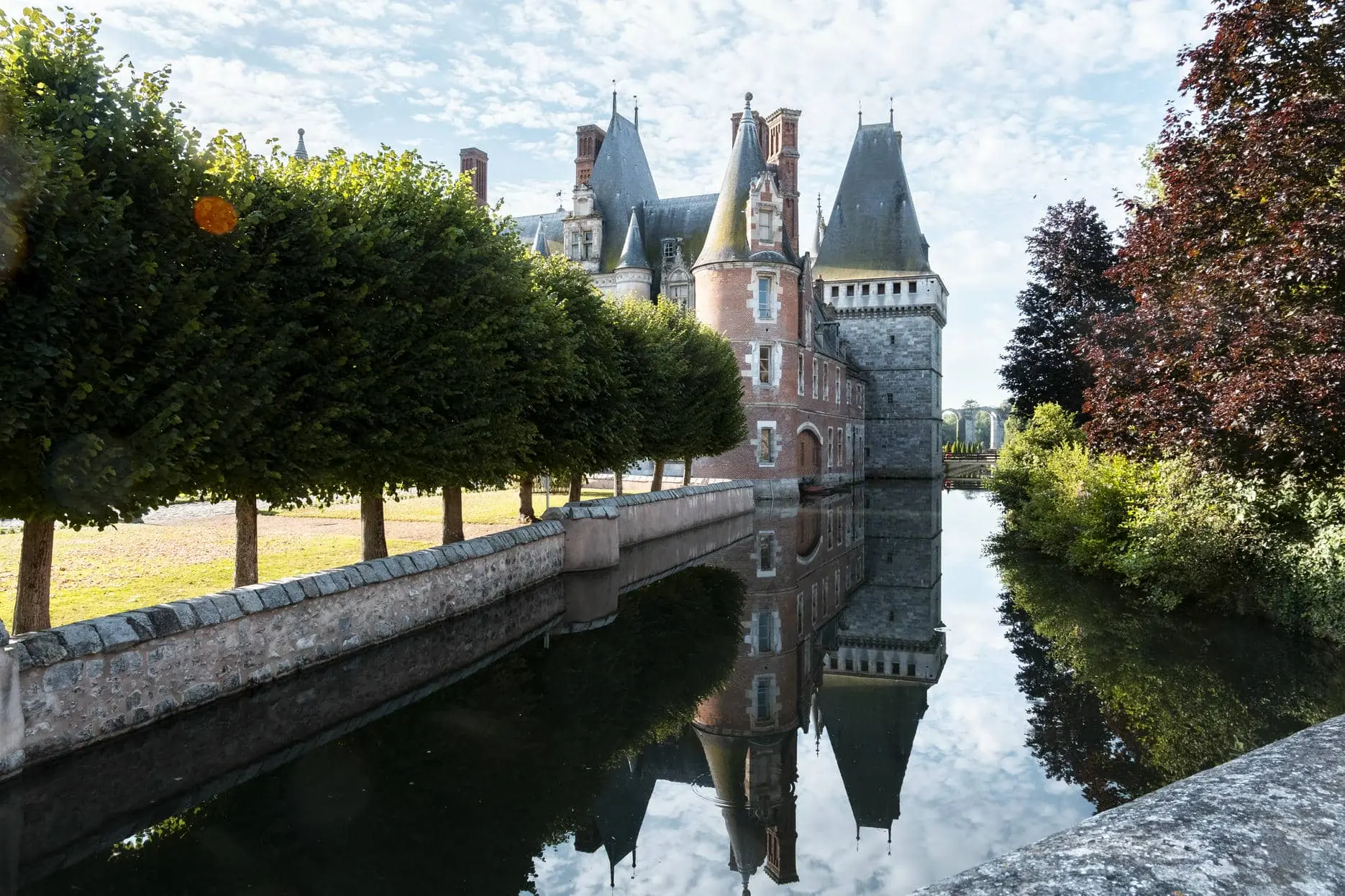 a castle is reflected in a body of water surrounded by trees