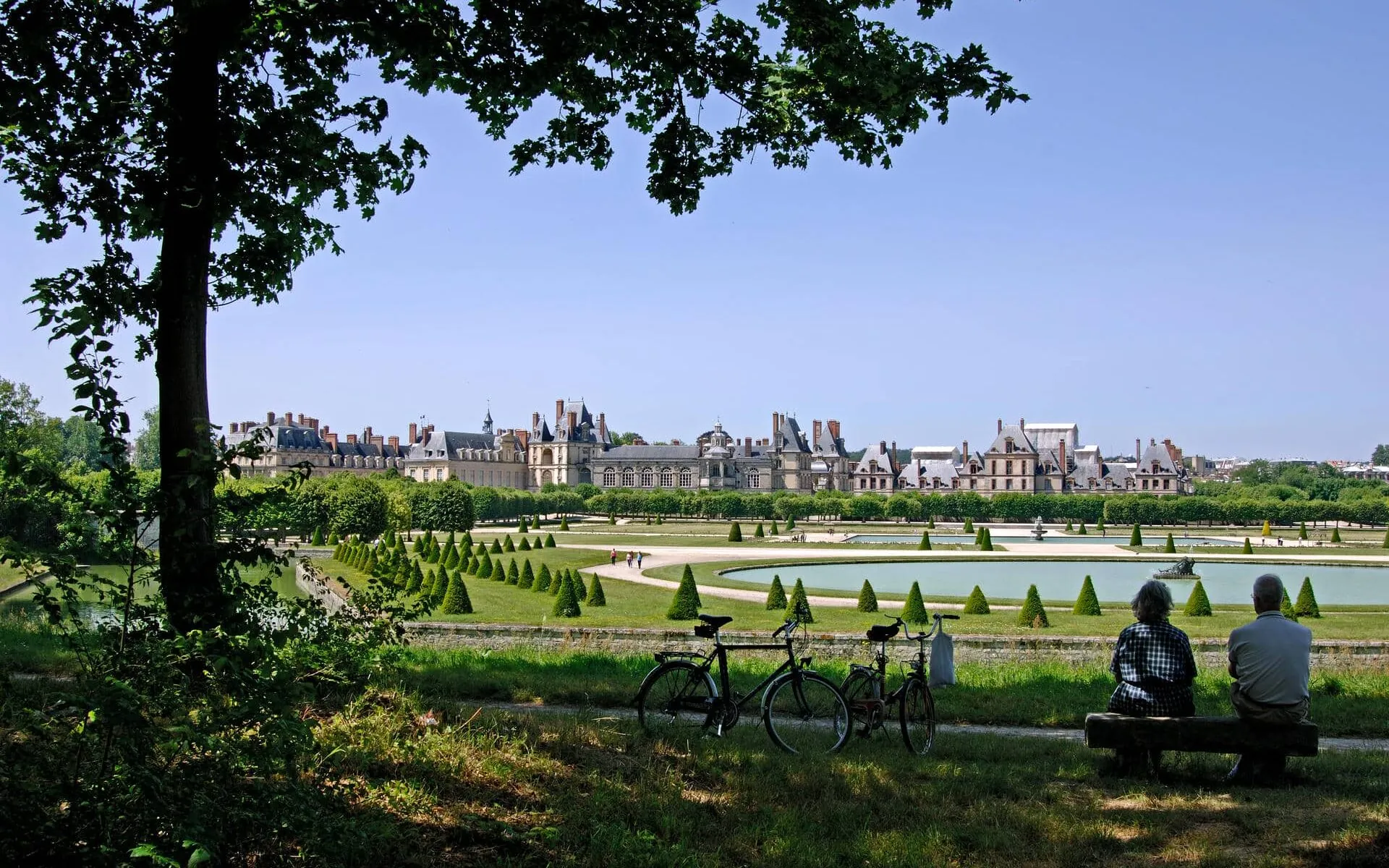 a man and woman sit on a bench in front of a castle