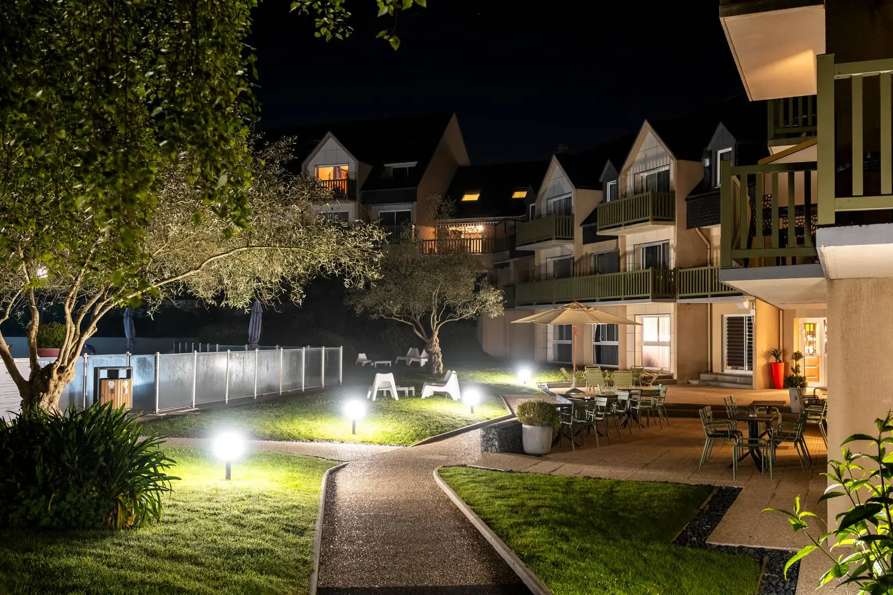 un patio avec des tables et des chaises est éclairé la nuit