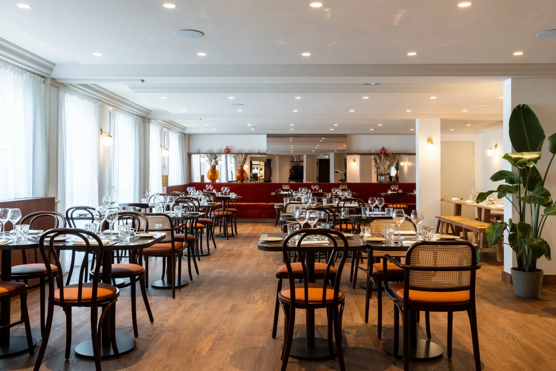 a restaurant overlooking the Champ de Mars, with vintage tables and chairs, red banquettes, and a wooden communal table at the back