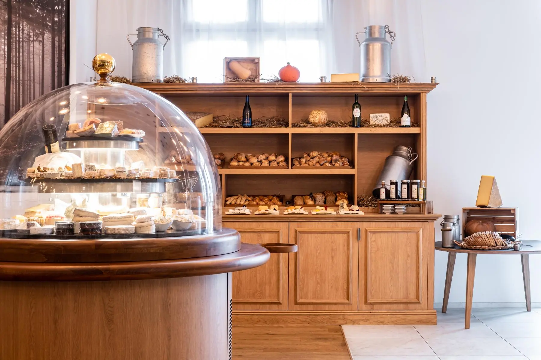 imposante cloche à fromages de 1,80 m, faisant face au corner boulangerie et mettant en valeur une sélection de pains et de pots de lait fermier du restaurant de l’hôtel